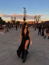 Vestido largo negro con escote profundo halter y diseño de transparencias en el torso. Presenta una falda con tajo lateral pronunciado y detalle de volados en el borde.