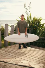 Remeron de algodón color verde musgo con efecto lavado, de manga corta y corte oversize. Presenta una estampa en la espalda con diseño inspirado en la playa, palmeras y flores, junto con la inscripción "Glassy Waves Club".