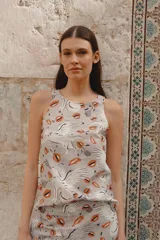 Musculosa gris con estampado de lobos, labios y figuras abstractas en negro y naranja. Cuello redondo y sisas amplias.