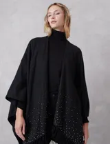 Ruana negra de tejido soft, con detalles de brillos y perlas en los extremos, y terminación con flecos.