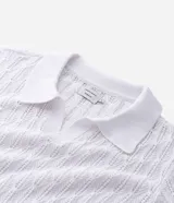 Polo de manga corta color blanco, con cuello en V y textura de rombos abiertos. Confeccionado en algodón.