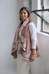 Chaleco abierto de textura suave, color rosa con diseño floral en relieve de color crema en los bordes y el interior. Presenta un corte holgado y fluido.