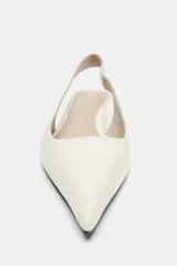 Zapato destalonado de piel color blanco, con tira trasera elástica, tacón de mini cuña y acabado en punta fina.