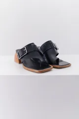 Sandalia color beige con tira ancha de cuero sobre el empeine, hebilla metálica plateada y taco geométrico de madera.