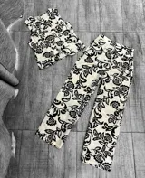 Conjunto blanco con estampado floral negro, compuesto por un chaleco con botones y un pantalón palazzo de tiro alto.