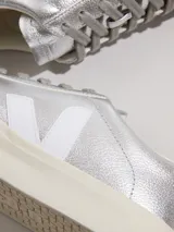 Championes Veja modelo Campo, confeccionados en cuero metalizado color plateado. Presentan el logo de la marca en los laterales en color blanco, cordones al tono y suela de goma en color crema.