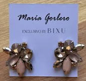 Par de caravanas con forma de flor, con cristales facetados en tonos lila, blanco y dorado.