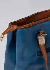 Cartera azul de cuero sintético con doble asa corta color marrón. Tiene dos compartimentos principales con cierre y bolsillos internos. Incluye correa larga extraíble.