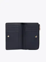 Billetera plegable Tommy Hilfiger color azul marino, de acabado granulado, con cierre de botón a presión, múltiples ranuras para tarjetas, compartimento para billetes y bolsillo exterior con cremallera. Presenta el monograma TH metálico en la parte delantera.