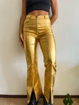 Pantalón dorado de tiro alto, corte ajustado hasta la rodilla y acampanado con aberturas en el ruedo.