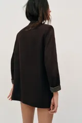 Blazer de lino color verde militar, con cuello solapa, hombreras y manga larga con puño revuelto con detalle a rayas. Cuenta con cierre frontal de un botón y bolsillos delanteros con solapa.