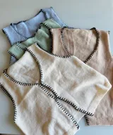 Chaleco tejido color arena con terminaciones en punto festón negro.