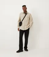 Camisa de corte regular, color beige, con cuello camisero, mangas largas, cierre frontal con botones y dos bolsillos con solapa en el pecho.