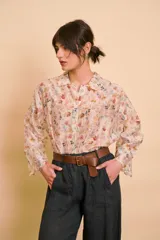 Camisa de manga larga color beige con delicado estampado floral multicolor, cuello camisero y cierre frontal de botones.