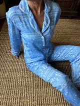 Pijama celeste de algodón estampado, compuesto por una camisa de manga larga con botones y vivo en contraste, y un pantalón recto con elástico en la cintura.