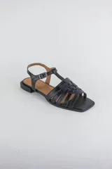 Sandalias de cuero color negro, de suela plana, con tiras entrelazadas en la capellada y tira ajustable en el talón con hebilla metálica.