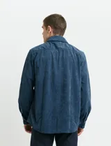 Sobrecamisa de pana color marrón, con manga larga, cierre frontal con botones y dos bolsillos frontales con solapa y botón.