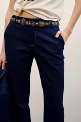 Pantalón sastrero de denim azul oscuro con costuras pespunteadas a contratono. Cuenta con cierre metálico frontal, gancho sastrero y botón en la cintura.