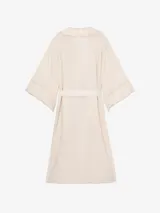 Kimono de lino color beige, de silueta fluida, con escote en V, mangas amplias, lazo para ajustar en la cintura y delicadas guardas de encaje en solapas y puños.
