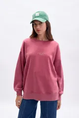 Buzo oversize color bordó con cuello redondo, mangas largas y puños y dobladillo acanalados. Estampado frontal con la frase "C'EST LA VIE PARIS" en color dorado.