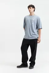 Remera marrón de manga corta con corte oversize y cuello redondo. Estampado en la espalda con diseño abstracto y texto.