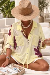 Camisa blanca de manga larga con estampado floral en tonos bordó y verde, cuello camisero, cierre frontal de botones y bolsillos en el pecho con apliques de lentejuelas.