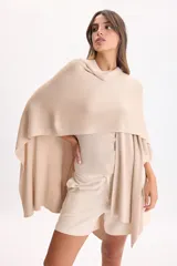 Ruana de punto color beige con hilos de lurex incorporados, diseño abierto y caída fluida.
