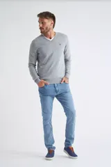 Sweater de tejido de punto color beige, con escote en V, mangas largas y puños y dobladillo acanalados. Presenta un pequeño logo bordado en el pecho.