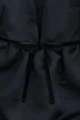 Top corto negro de satén con escote en V pronunciado, breteles finos dobles, detalle de ribete y moño de terciopelo bajo el busto, y diseño abullonado en la parte inferior.