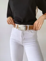 Cinto de cuero color camel con forro de cuero y hebilla rectangular de guampa con borde metálico trenzado. Cuenta con broche suizo intercambiable.