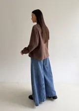 Camisa color marrón chocolate con bordado artesanal de flores y hojas en hilo crudo. Presenta cuello con volado, mangas largas con puños abotonados y cierre frontal con botones.