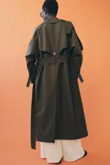 Trench oversize de Zara Woman Collection, color verde militar, con cuello solapa, cierre frontal cruzado con botones y cinturón ajustable del mismo tejido. Presenta mangas largas con trabillas ajustables y bolsillos delanteros.