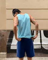 Musculosa sin mangas color beige claro con cuello redondo y estampa frontal con el logo de Umbro en rojo con patrón de líneas diagonales.