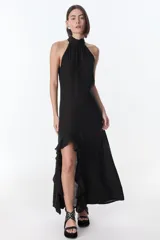 Vestido largo de lino italiano, color negro, con escote halter y diseño sin mangas. Presenta una abertura lateral con detalle de volados que recorre el frente.