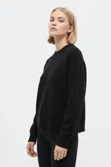 Sweater negro de punto liso, de corte holgado, con cuello redondo a la base y mangas largas.