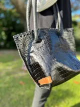 Cartera de cuero con textura crocco en color rojo, de silueta estructurada, manijas largas marrones y detalles de terminación artesanal en el borde superior.