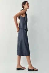 Chaleco cruzado confeccionado con lino de color azul marino, con cuello redondo, manga sisa, bajo con pinzas y cierre frontal con botones dorados.
