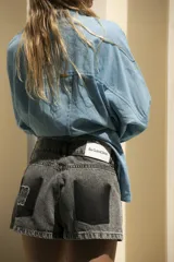 Short de jean gris oscuro con efecto degradé simulando los bolsillos y parche negro con logo bordado en el bolsillo trasero.