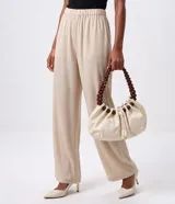 Cartera hobo marca Satinato en poliuretano color marfil, con diseño fruncido, cierre de cordón ajustable y asa rígida de esferas de madera.