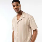 Camisa de manga corta color beige con diseño de rayas verticales blancas, cuello tipo cubano y cierre frontal con botones.