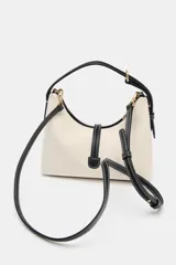 Bolso de mano tipo saca, color borgoña, con asa de mano ajustable y correa bandolera extraíble. Presenta un detalle de doble tira con terminaciones de bolas metálicas doradas en el frente.