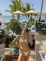 Top de bikini triangular color negro, con textura acanalada y detalle de argolla de resina en el centro. Cuenta con breteles finos para atar en la espalda y forro interior.
