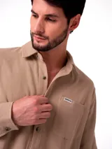 Camisa de manga larga Caterpillar confeccionada en tejido waffle, color beige, con cuello clásico, cierre frontal de botones y bolsillo en el pecho con etiqueta de la marca.