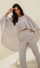 Conjunto color gris compuesto por un top corto con mangas anchas y un pantalón de vestir de tiro alto con bolsillos laterales.