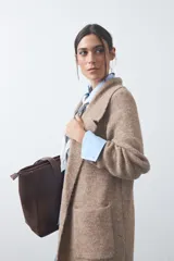 Cardigan de tejido de punto gris, con silueta larga, frente abierto, solapas clásicas y bolsillos aplicados en los laterales.