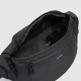 Riñonera negra con diseño funcional de tres compartimentos con cierre. Cuenta con correa ajustable con hebilla de seguridad, permitiendo su uso tanto en la cintura como cruzada al pecho.
