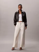 Pantalón de sarga color beige, de corte regular y pierna ancha, con franjas laterales con el logo de Calvin Klein y bolsillos laterales.