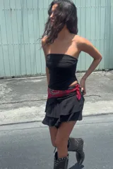 Falda pantalón corta de tiro medio, color negro, con cintura elástica en la espalda. Presenta detalle de tachas metálicas en la parte delantera y diseño de volantes a tono. Incluye forro interior.