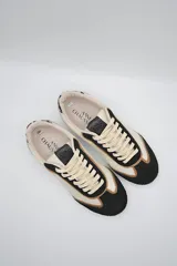 Zapatillas urbanas de cuero color beige y blanco con detalles en animal print en el talón y cordones marrones.