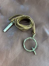 Collar de tiento de cuero con dije en forma de letra y placa metálica con inscripción.